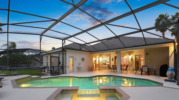 An indoor swimming pool with a glass ceiling, surrounded by a patio area with chairs and a table. - Experience magic! HR Golf Course view 5bd/3b w/pool-spa near all Disney Parks (Davenport)
