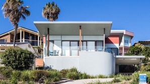 A modern building with a flat roof, large windows, and a circular structure in the center. - 18 Cliff Road - Opposite One Mile Beach! (Forster)