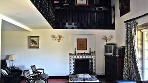 A spacious living room with a fireplace, a high ceiling, and a staircase leading to an upper level.