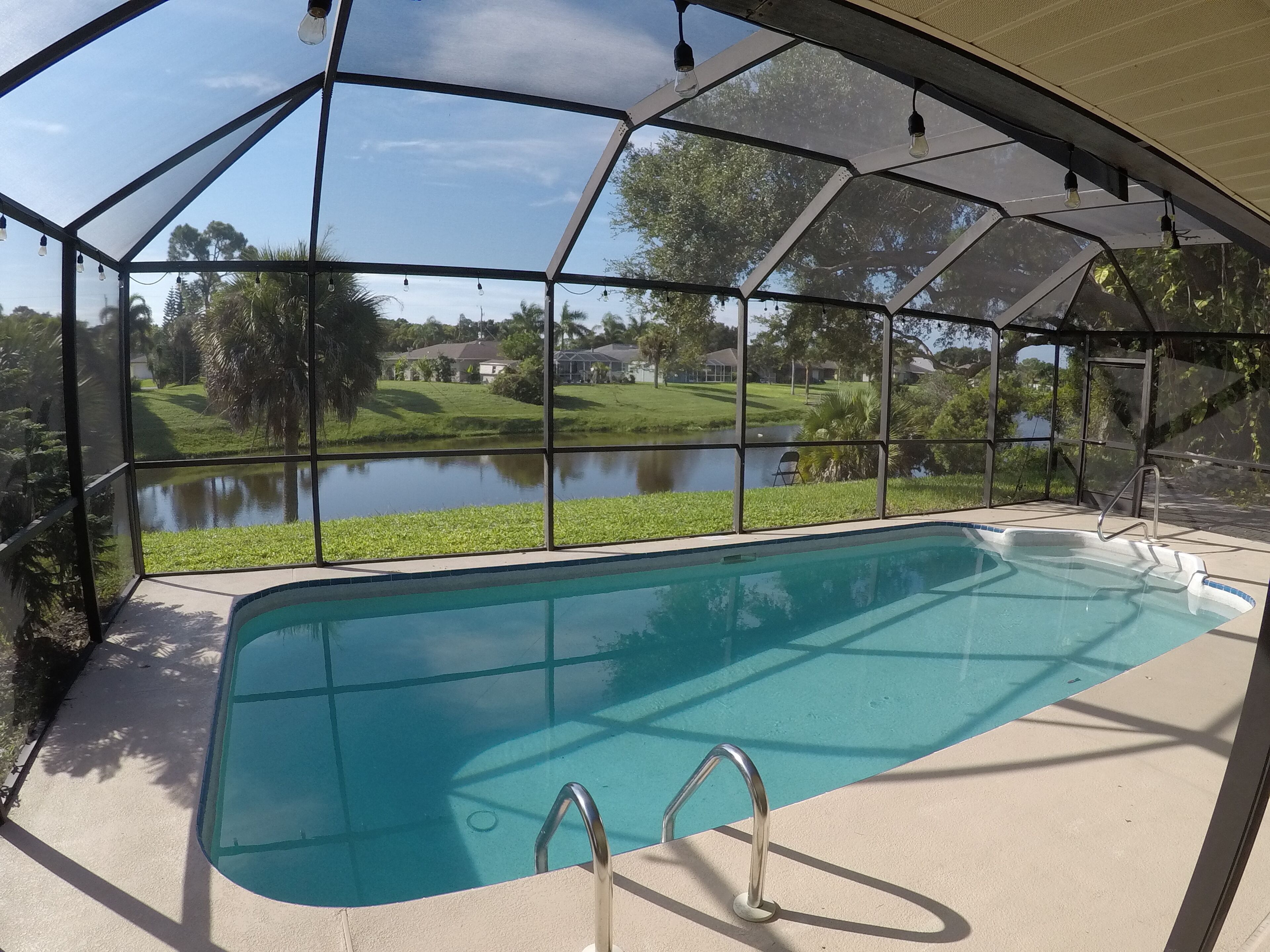 A covered swimming pool with a view of a lake and houses in the background.