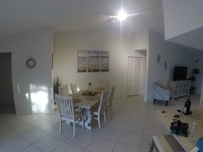 A dining area with a round table, white chairs, and a painting above.