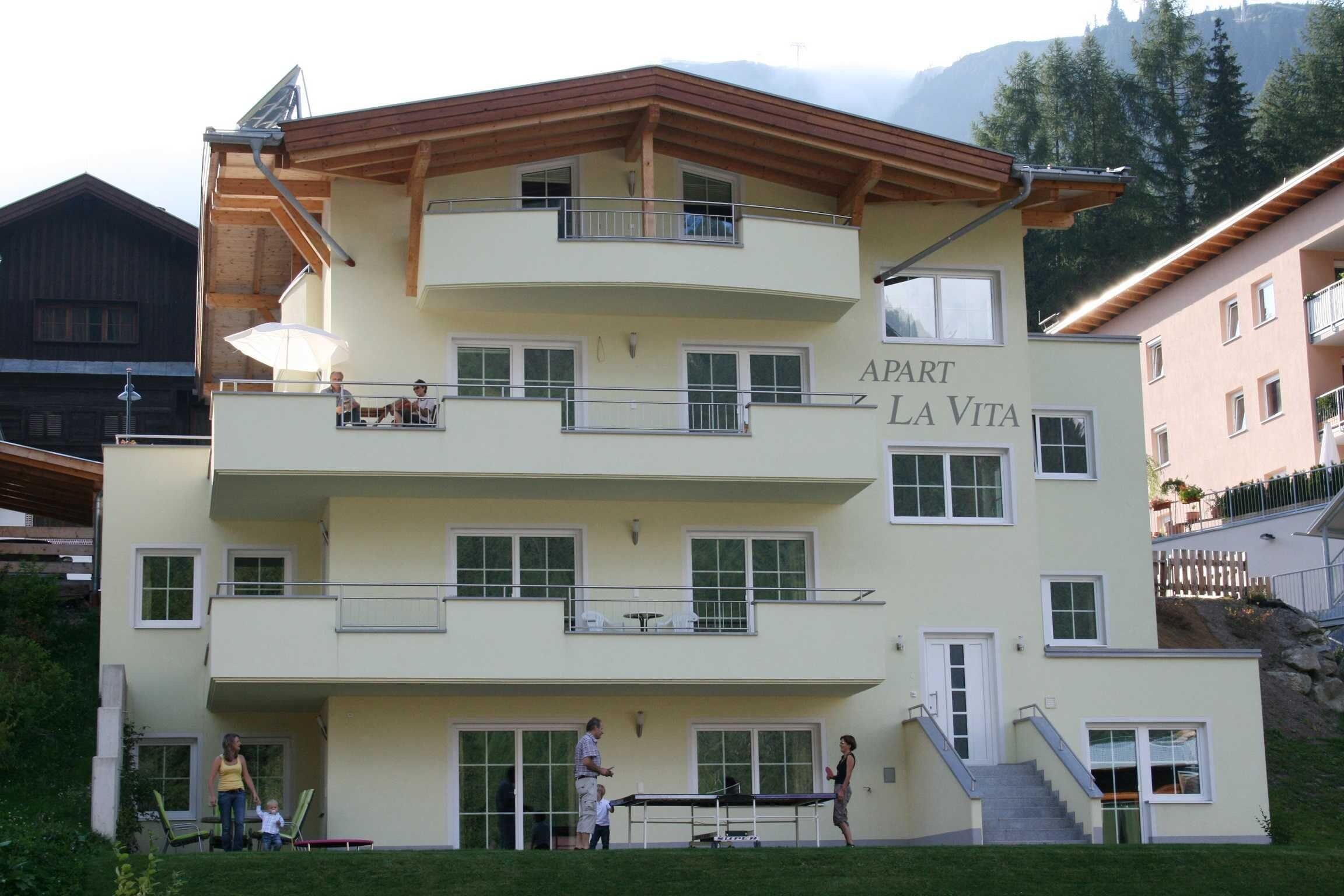 A multi-story building with balconies, a sign reading "APART LA VITA," and a staircase leading to the entrance.