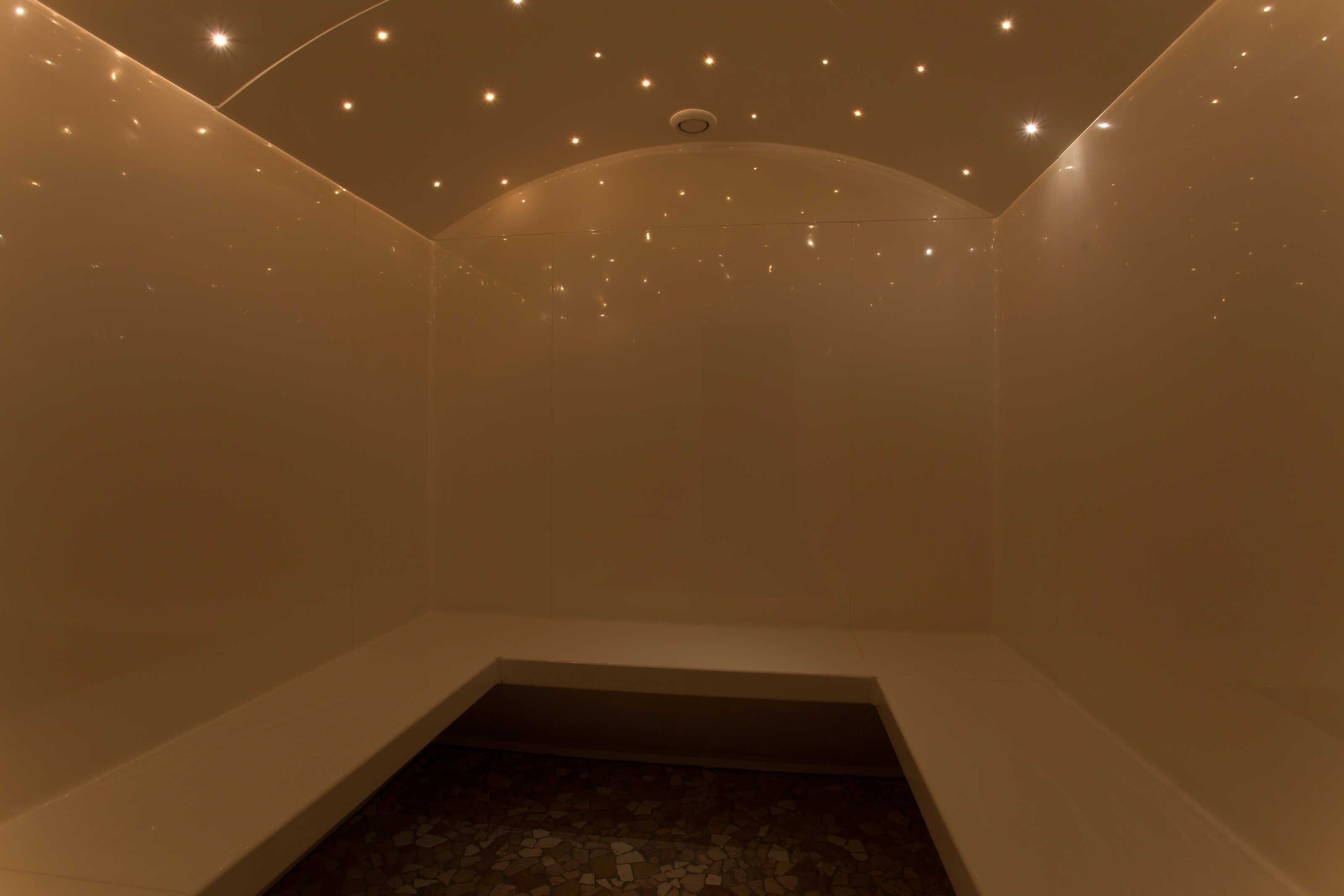 Ein Zimmer mit schrägverdeckter Decke, eingelassener Beleuchtung und einem zentralen Oberlicht.