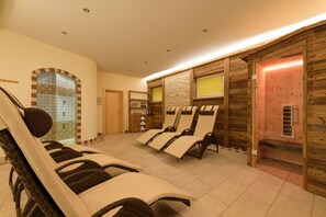 A spa area with reclining chairs, a small reception desk, and a wooden wall with a window. - Suite Mariella - Apart La Vita (Sankt Anton am Arlberg)