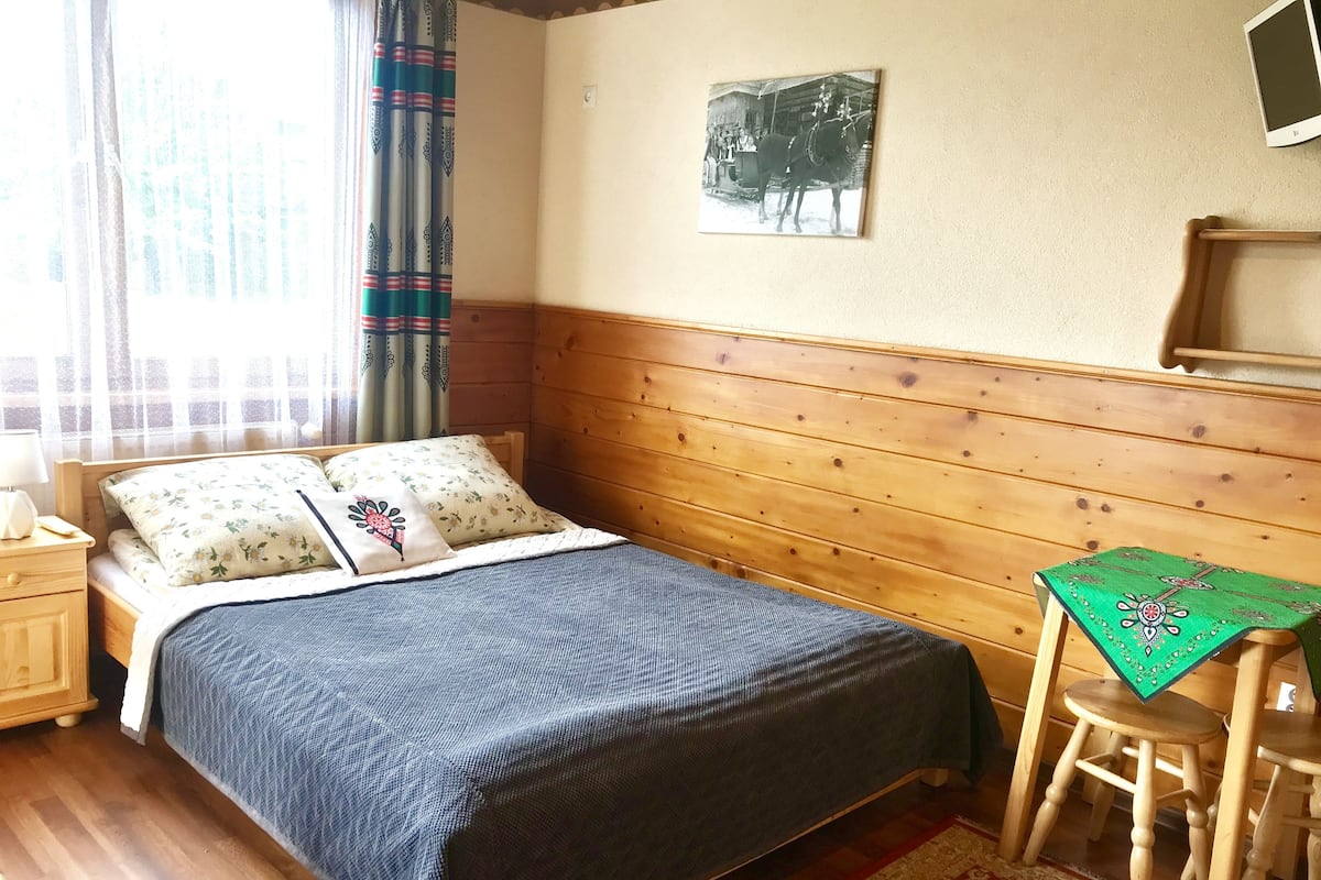 Ein Zimmer mit Holzwänden, einem Bett, einem kleinen Tisch und einem Stuhl.