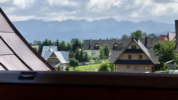 Vista desde una ventana con vistas a un pueblo con casas tradicionales y montañas al fondo.