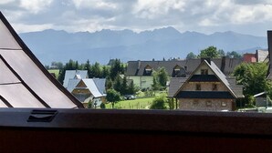A view from a window overlooking a village with traditional houses and mountains in the background. - Pokoje goscinne u Jaska (Poronin)
