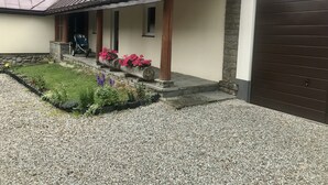 Un edificio con un porche cubierto, pilares de piedra y un camino de entrada de grava.