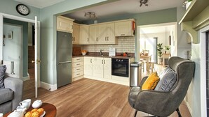Una cocina moderna con armarios blancos, un refrigerador de acero inoxidable y un horno empotrado.