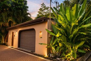 A building with a closed garage door, a small window, and a paved driveway. - Villa Colibrí, 3 BR, walk to beach, private pool (Santa Teresa Beach)