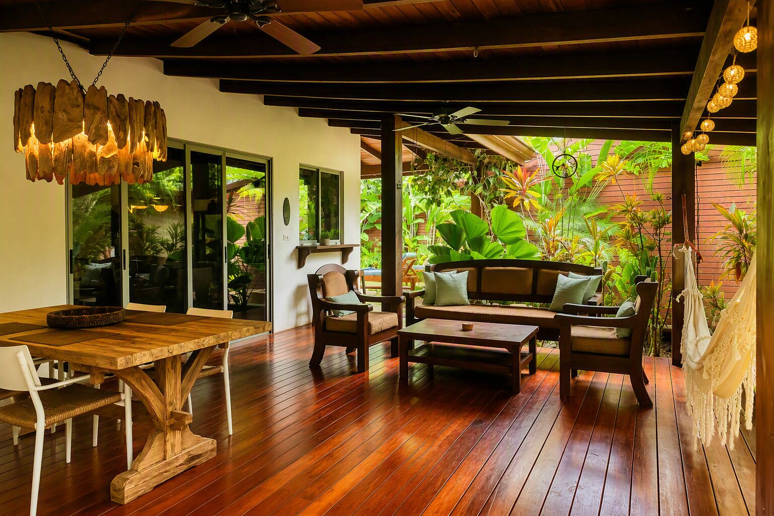 A wooden deck with a dining table and chairs, a sofa, and a hanging light fixture.
