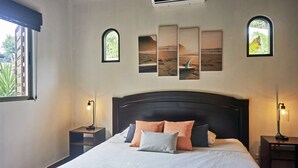 A neatly made bed with a white and grey bedspread, two nightstands with lamps, and a large window with blinds. - Villa Colibrí, 3 BR, walk to beach, private pool (Santa Teresa Beach)