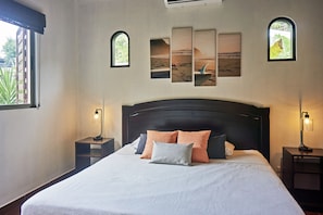 A neatly made bed with a white and grey bedspread, two nightstands with lamps, and a large window with blinds. - Villa Colibrí, 3 BR, walk to beach, private pool (Santa Teresa Beach)