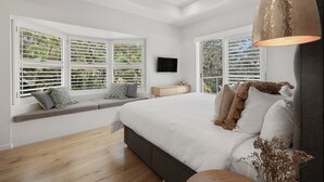 A bedroom with a large bed, a ceiling fan, and a window seat with a TV. - Audrey - Little Cove (Noosa Heads)