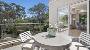 A modern balcony with a round table, chairs, and a potted plant. - Audrey - Little Cove (Noosa Heads)