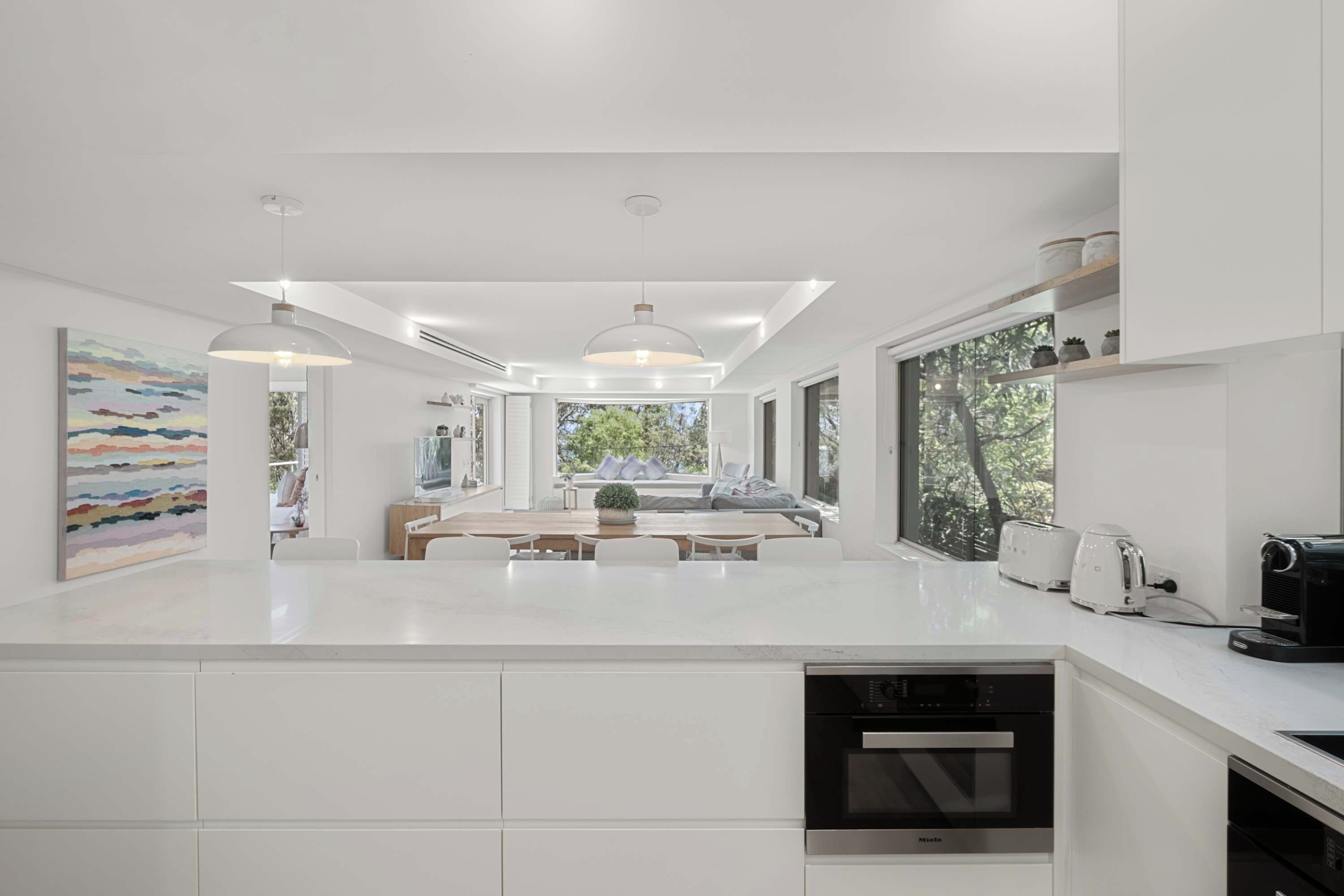 A modern kitchen with white cabinetry, a central island, and built-in appliances.