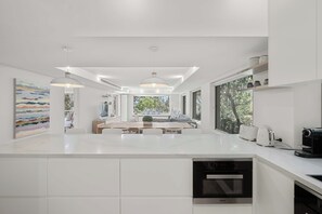 A modern kitchen with white cabinetry, a central island, and built-in appliances.