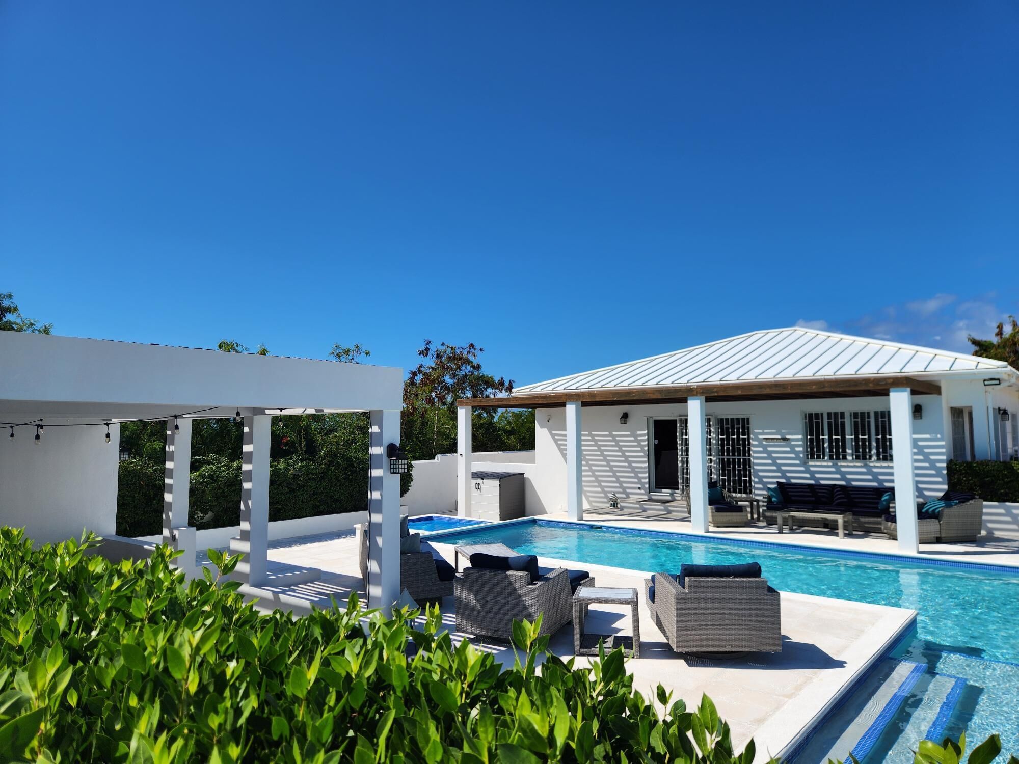 Ein moderner Poolbereich im Freien mit Liegestühlen und einer Pergola.