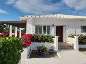 A white house with a brown door, a covered porch, and potted plants. - 10% off nightly rate Promo for stay: Aug 10 to Nov 10 2026
Private Villa & Pool (Long Bay)