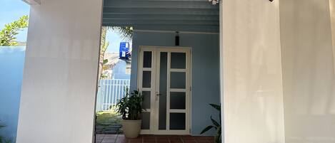 A covered outdoor area with a tiled floor, a door, and a potted plant.