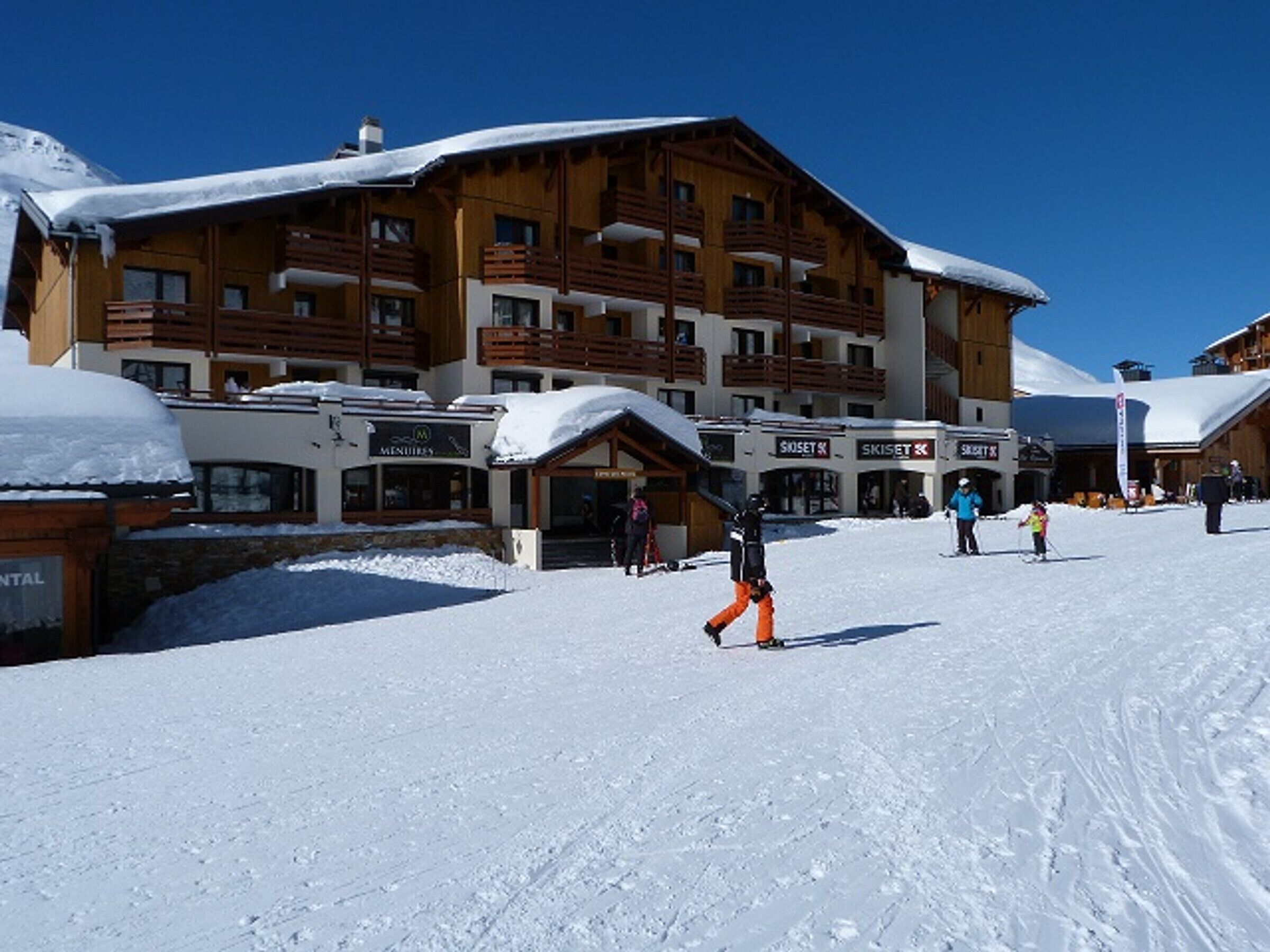 Ein Skigebäude mit mehreren Balkonen und einer Seilbahn im Hintergrund.