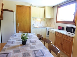 A compact kitchen with a dining table, chairs, a microwave, a toaster, and a sink.