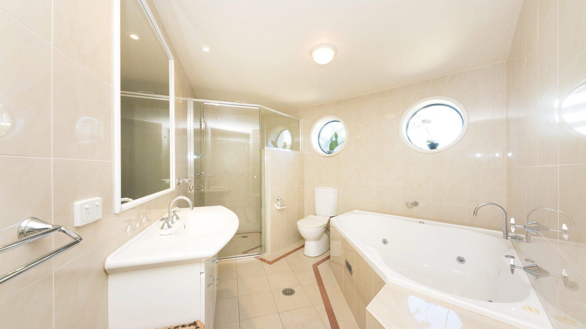 A modern bathroom with a glass-enclosed shower, a standalone bathtub, and a toilet.
