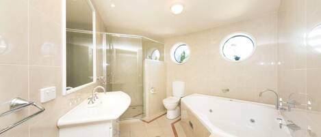 A modern bathroom with a glass-enclosed shower, a standalone bathtub, and a toilet.