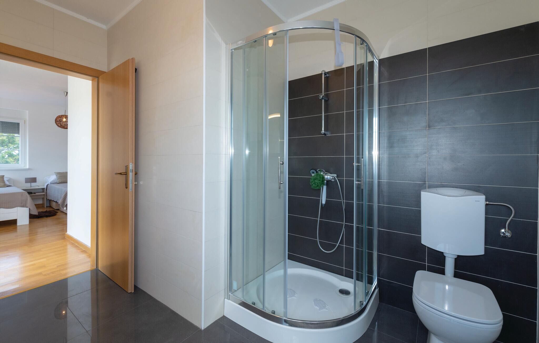 A modern bathroom with a glass-enclosed shower, a toilet, and a sink.