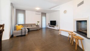 Un salon moderne avec un canapé, un téléviseur, une cheminée et des tabourets en bois.