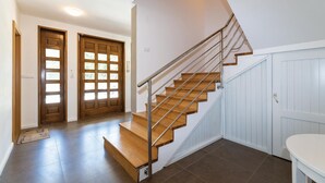 Un escalier avec des marches en bois et des rampes en métal, menant à un palier doté de deux portes en bois.