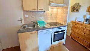 A compact kitchen with a dishwasher, oven, and a small sink. - Cozy 3-Room Apartment for 5 with Ski-In/Ski-Out, Balcony, and Modern Amenities (Les Menuires)