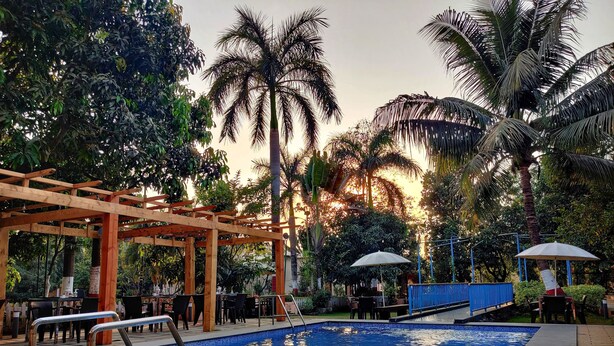 Un área de piscina con una pérgola de madera, sillones de descanso y sombrillas.