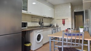 Una cocina moderna con electrodomésticos de acero inoxidable, lavadora integrada y comedor con mesa y sillas.