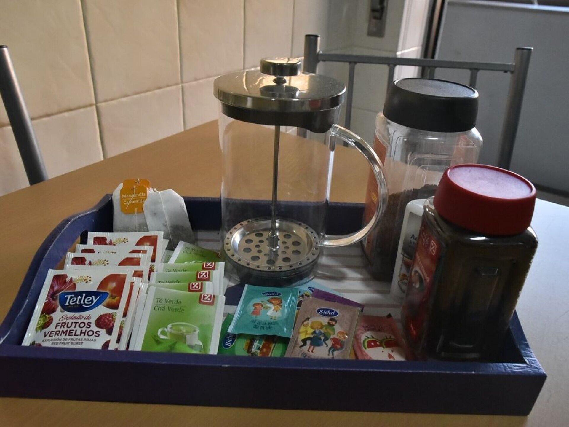 Una cuina amb un taulell, una cafetera, un bocal d'espècies i un plat amb aliments com a tè i aperitius.
