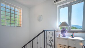 Una habitación con escalera, ventana con vistas y cómoda blanca con cajones.
