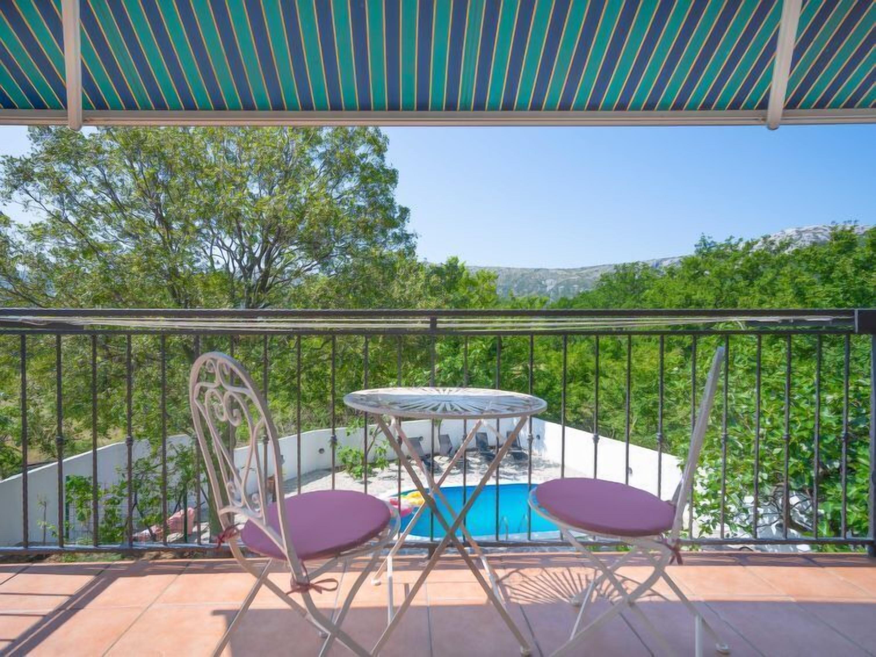 Un balcon avec une piscine, deux chaises et une table.