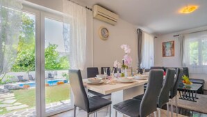 Un comedor con una mesa grande, sillas y vistas a una piscina y jardín.
