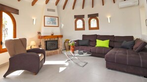 Ein Wohnzimmer mit Kamin, einer Couch, einem Sessel und einem Couchtisch.