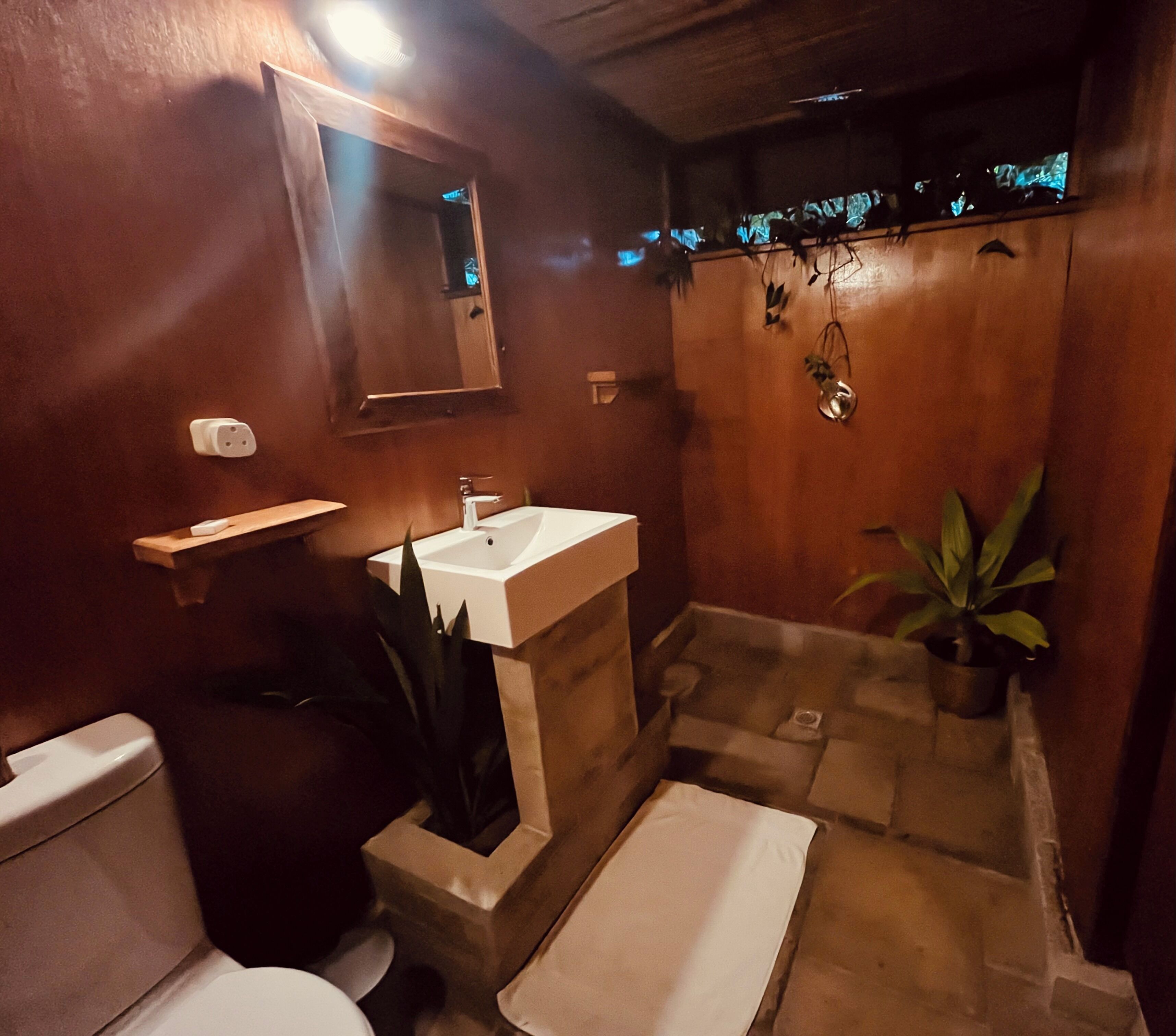 A bathroom with a toilet, sink, and shower area.