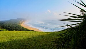 A coastal landscape with a beach and grassy area. - Sky Island Resort (Ponta d'Ouro)