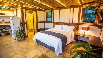 A bedroom with a bed, bedside table, lamp, and a window.