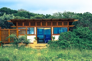 Una casa tradicional japonesa con estructura de madera, ventanas amplias y un jardín.