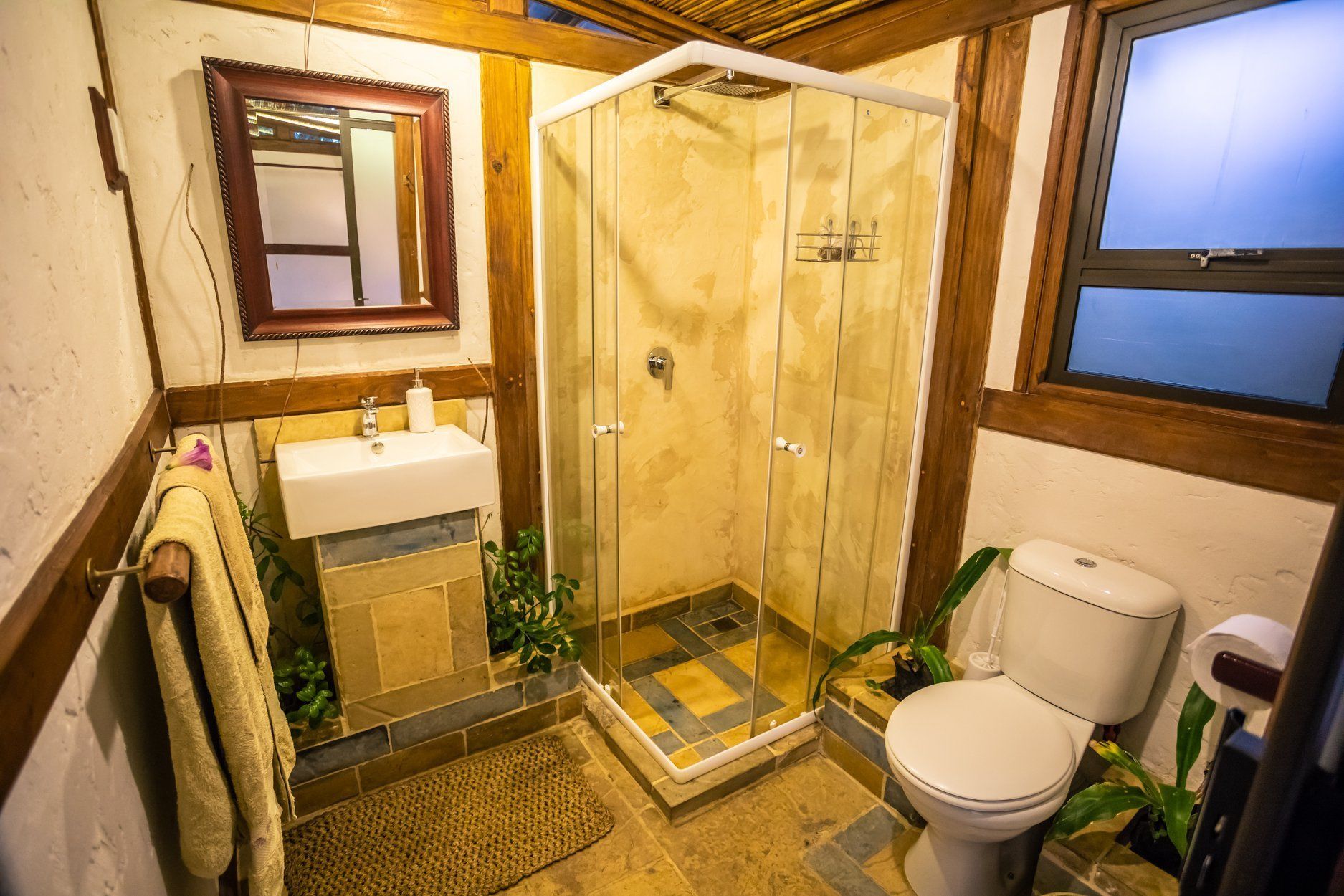 A bathroom with a shower, toilet, sink, and mirror.