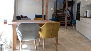 Cocina moderna con mesa y sillas de madera, una escalera y vistas al exterior.