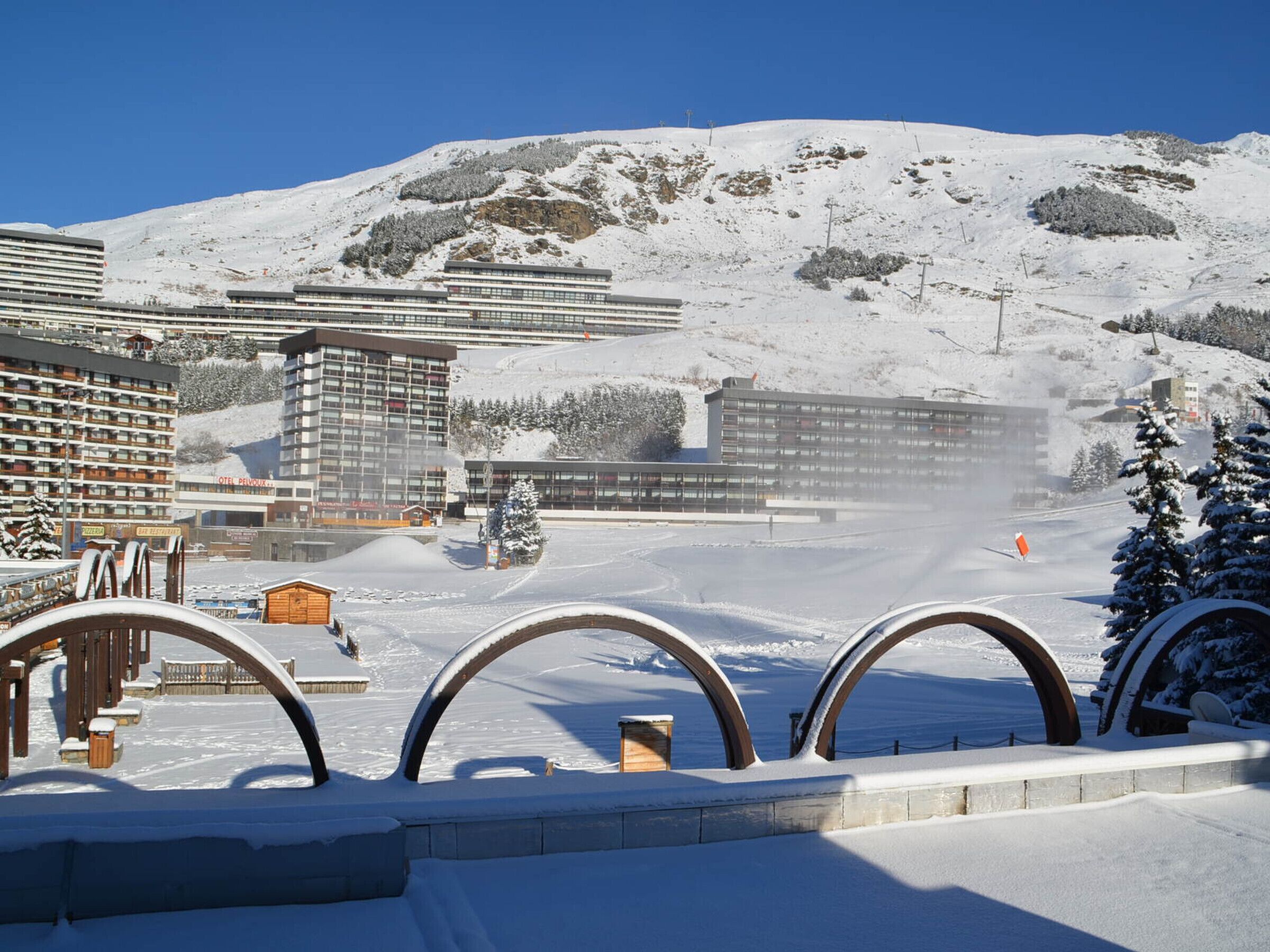 Et sneklædt skiområde med moderne bygninger, heriblandt et hotel og en restaurant.