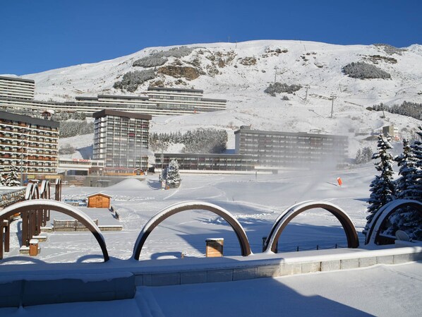 A snow-covered ski resort with modern buildings, including a hotel and a restaurant.