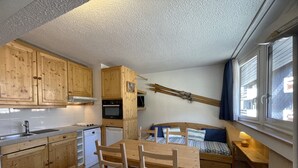 A compact kitchen with wooden cabinets, a dining table, and chairs. - Classic apartment for 4 at La Croisette (Les Menuires)