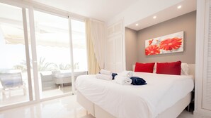 Una habitación de hotel con una cama grande, una puerta corrediza de vidrio a un balcón y un cuadro en la pared.