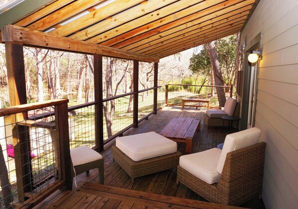 A covered outdoor seating area with wicker furniture and a wooden deck.